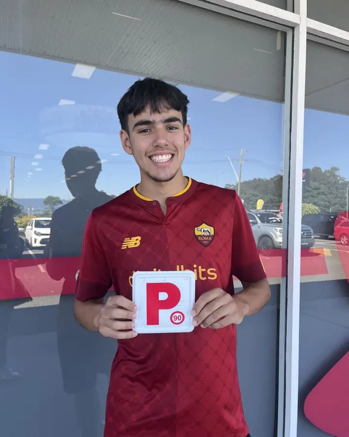 A student holding his P plate outside Service NSW