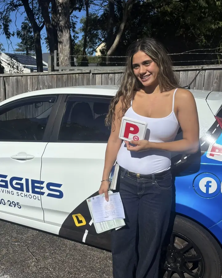 A student with her P plate and test sheet beside Reggie's car