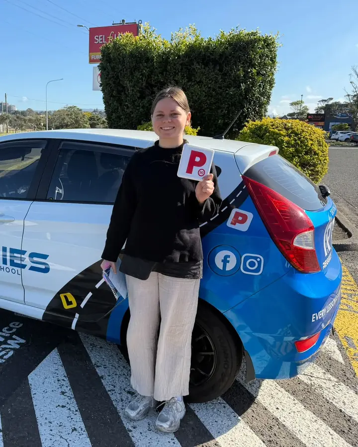 A student with her P plate beside Reggie's car at Service NSW