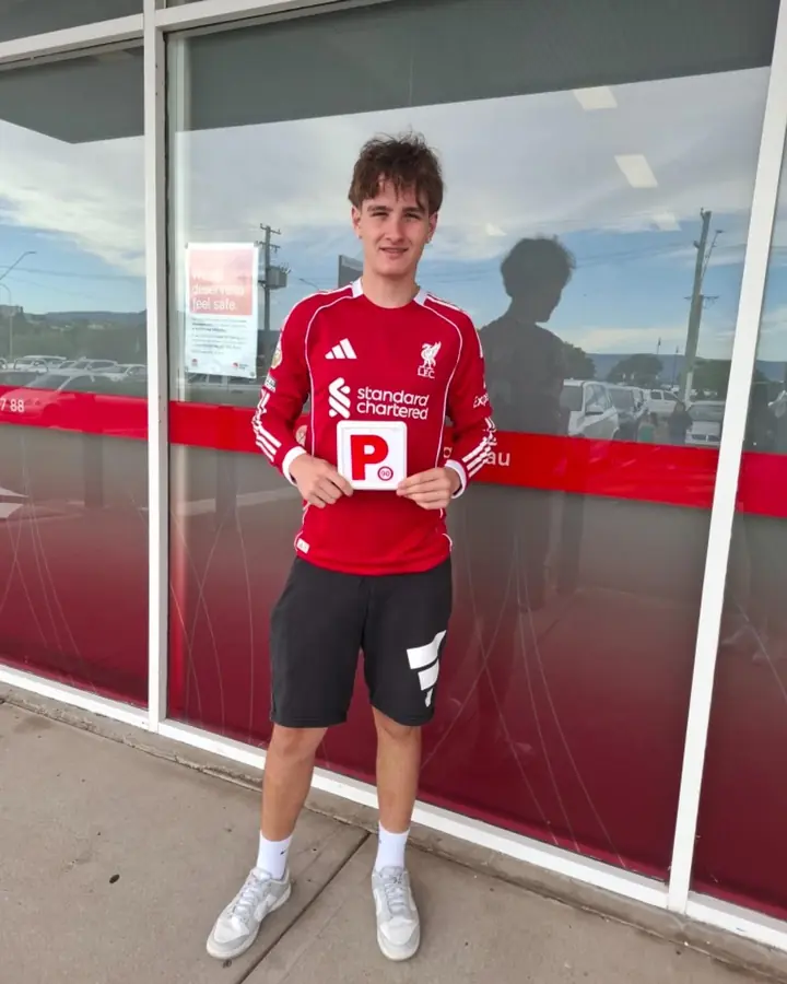 A student holding his P plate outside Service NSW